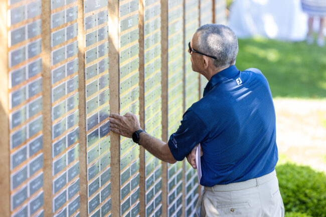 Man locating a plaque on Emilson Family Wall of Remembrance