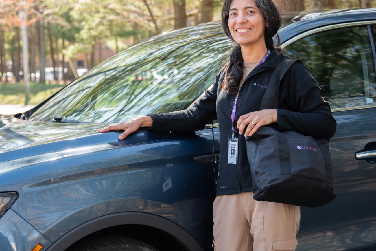Home health aide in front of car